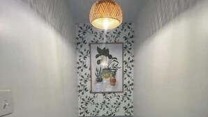 A narrow staircase with a wooden handrail, a hanging pendant light, and a framed botanical print on the wall. - 🌟 Trendy & Private Basement Studio 🌟 (Puyallup)