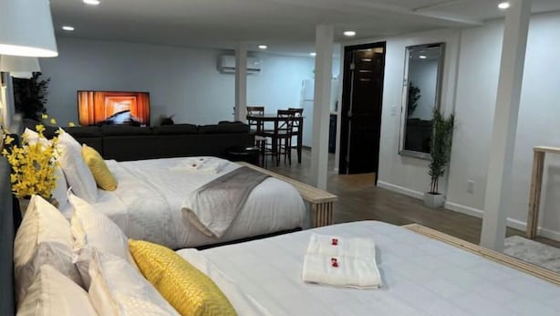 A hotel room with two beds, a sofa, a TV, and a dining area in the background. - 🌟 Trendy & Private Basement Studio 🌟 (Puyallup)