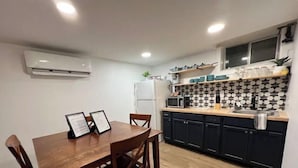 A modern kitchen with dark cabinets, a wooden dining table, and a tiled backsplash. - 🌟 Trendy & Private Basement Studio 🌟 (Puyallup)