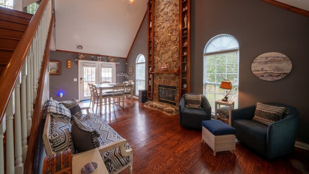 A spacious living area with a fireplace, wooden flooring, and a high ceiling fan. - Fish and Frolic – Lakefront w/Boathouse & Firepit (Scottsboro)