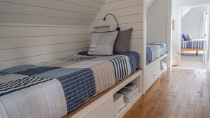 Un lit simple avec une couvre-lit matelassé, une tête de lit et une table de chevet avec une lampe.