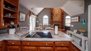 A kitchen with wooden cabinets, a marble countertop, and a stone fireplace. - Fish and Frolic – Lakefront w/Boathouse & Firepit (Scottsboro)