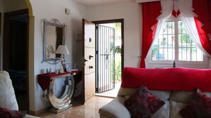A room with a red sofa, a mirror, a lamp, and a view of the outdoors through a window with red curtains. - 2.5 Bed 2 Bath Home, Private Pool & Spacious, Sun, Beaches & Golf (Orihuela Costa)
