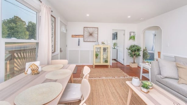 A modern living room with a dining area, a sofa, a coffee table, and a view of the outdoors.