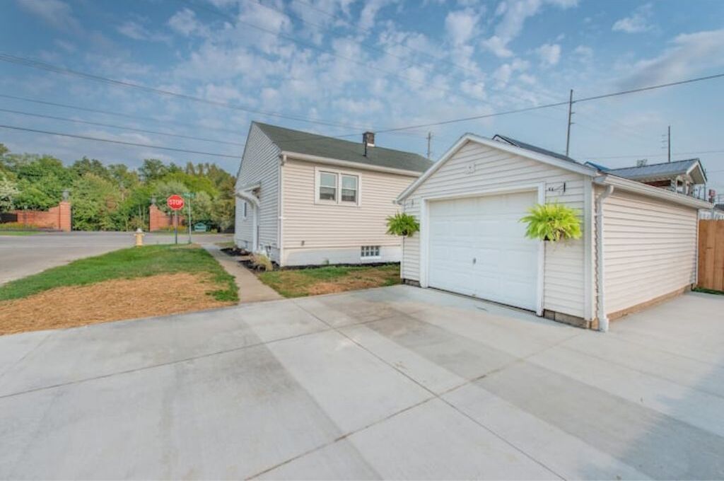 A single-story house with a garage, a front yard, and a stop sign in the background.