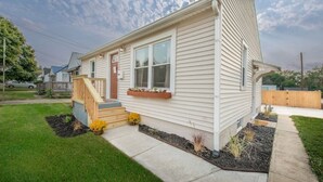 A single-story house with a front porch, a small deck, and a window with a flower box.