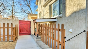 A residential property with a red gate, wooden picket fence, and a concrete pathway leading to a house with a stone facade. - 3 Mi to Dtwn: Convenient Denver Apt (Denver)