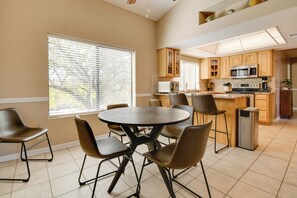 A modern kitchen with wooden cabinets, a stainless steel microwave, and a round dining table with six chairs.