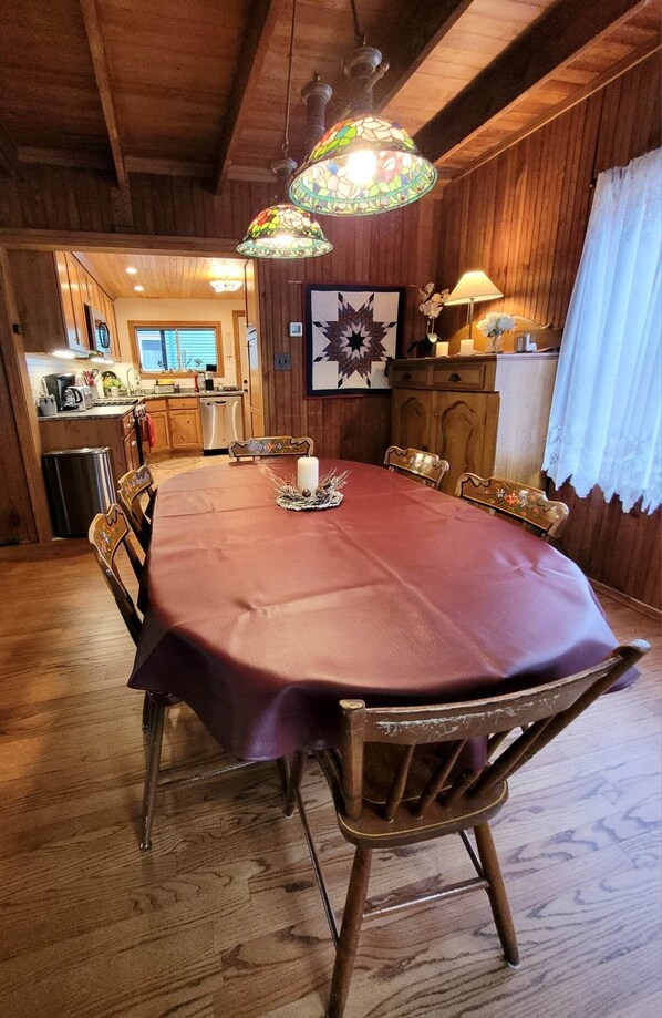 A wooden dining room with a large table, chairs, and a chandelier.