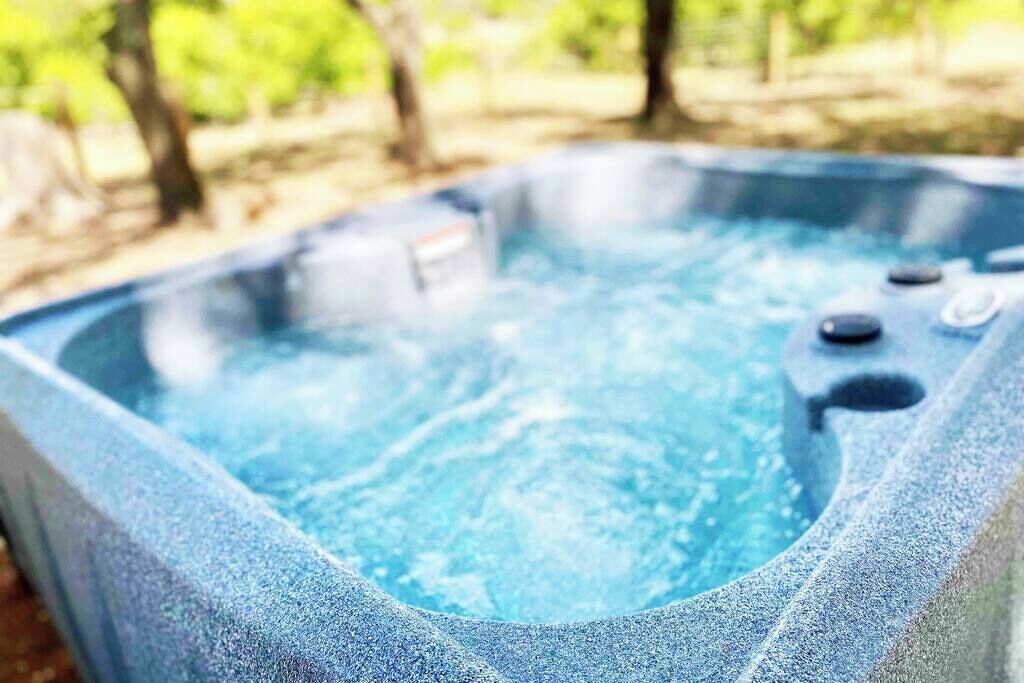 A hot tub with a stone exterior and a clear blue interior, surrounded by trees.