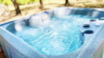 A hot tub with a stone exterior and a clear blue interior, surrounded by trees.