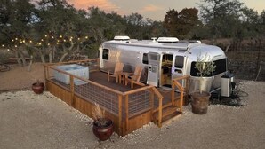 Una caravana estacionada con terraza, asientos y una pequeña mesa.