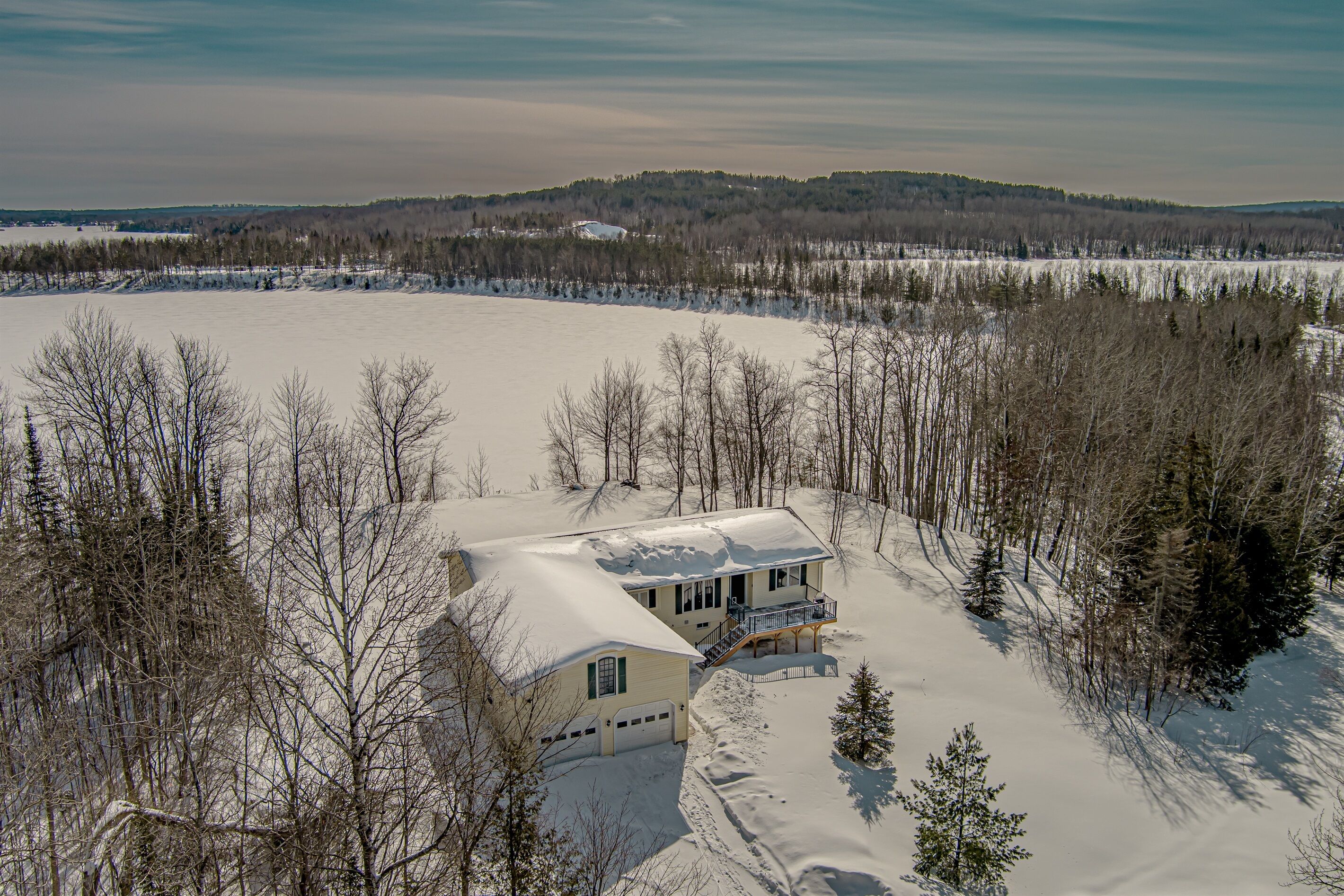 A snow-covered landscape with a house surrounded by trees.