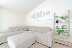 A modern living room with a sectional sofa, a small side table, and a wooden ladder shelf with decorative items.
