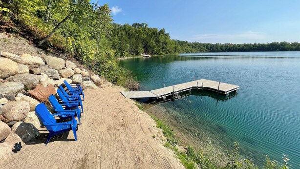 A lakeside dock with blue chairs and a sandy path.