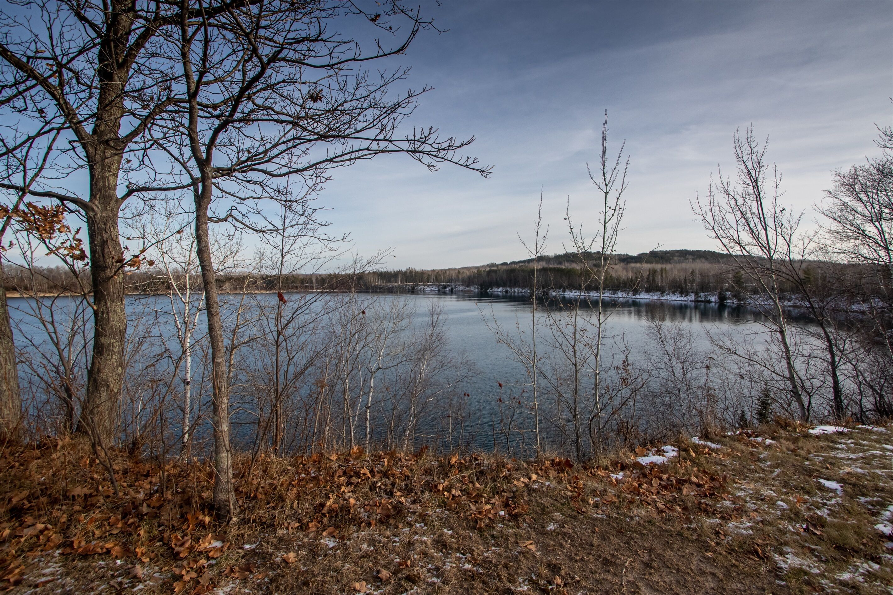 A lake surrounded by trees and a hilly landscape.