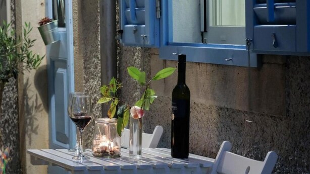 Une table avec une bouteille de vin, deux verres et un petit vase avec des fleurs.