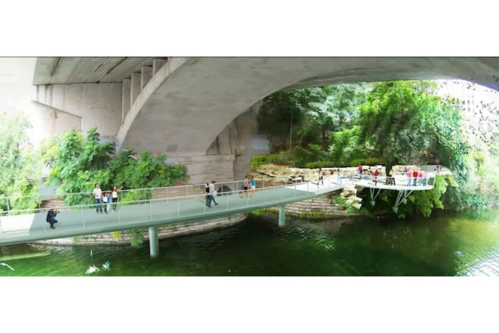 A pedestrian bridge over a river with people walking.