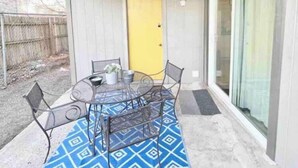 A covered patio with a table and chairs, a yellow door, and a sliding glass door. - Relax South Central *5 mi from downtown* VB (Austin)