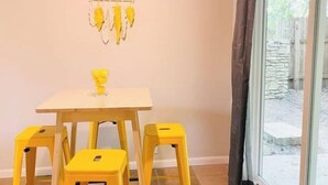 A room with a table and four yellow stools, a hanging decoration, and a view through a window with curtains. - Relax South Central *5 mi from downtown* VB (Austin)