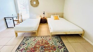 A small, bright room with two single beds, a small desk, and a round mirror on the wall. - Relax South Central *5 mi from downtown* VB (Austin)