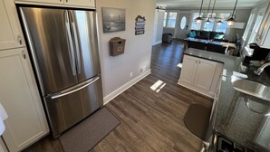 A modern kitchen with stainless steel appliances, wooden flooring, and a view to the living area. - Perfect Lake House Getaway! (Waterford)