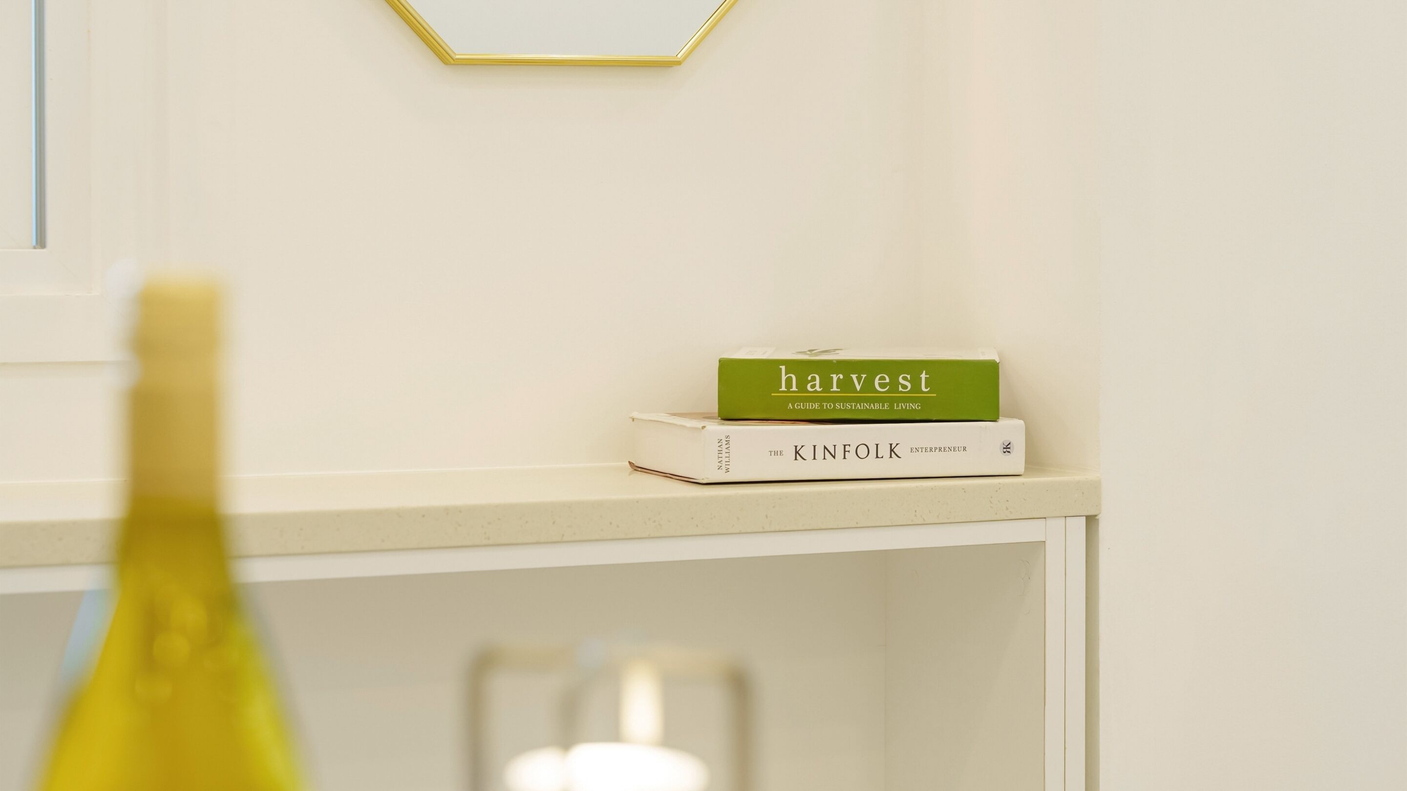 A white shelf with two books, one titled 'harvest' and the other 'the kinfolk.'