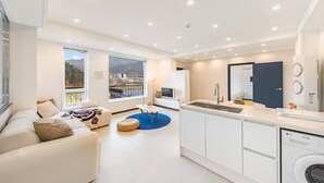 A modern apartment with a living area, kitchenette, and a view of a mountainous landscape. - Gapyeong Haneul Sanchaek Poolvilla Pensi (Gapyeong)