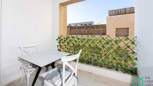 Un balcon avec une table et des chaises, une clôture en bois et une vue sur des bâtiments en arrière-plan.