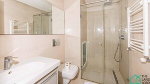 Une salle de bain moderne avec une douche à parois de verre, un lavabo blanc et des toilettes.