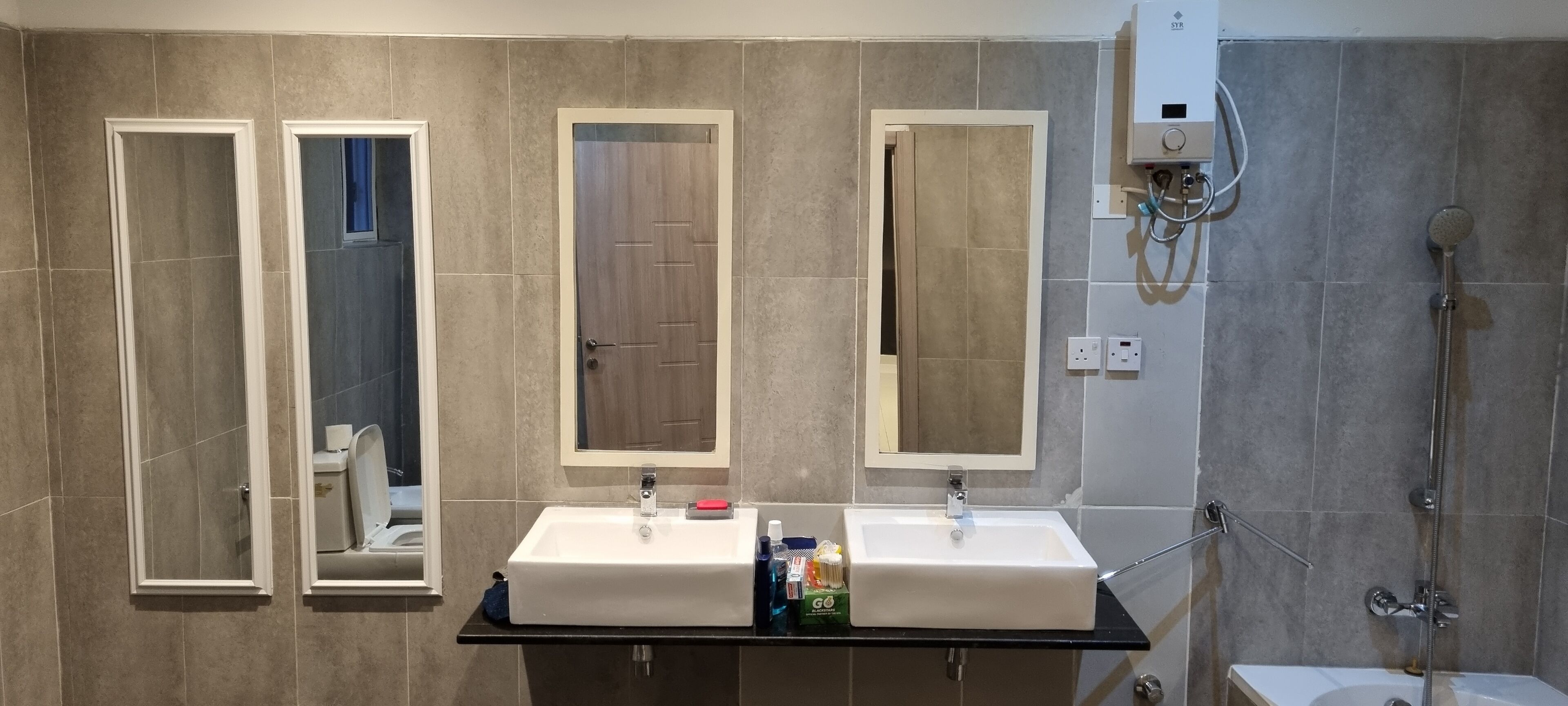 Une salle de bain moderne avec deux lavabos, une douche et trois miroirs.