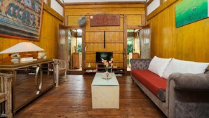 A traditional wooden interior with a sofa, a coffee table, and a television. - Villa Pagoda (Legian)