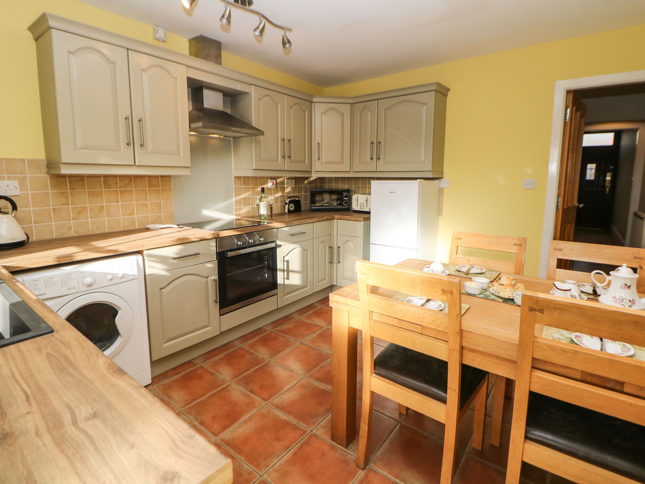A compact kitchen with a washing machine, oven, microwave, and a dining area with a table and chairs.