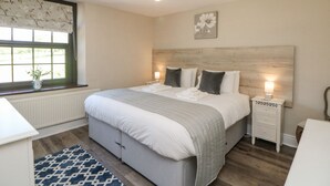 Quarto com uma cama grande, mesas de cabeceira, uma janela com vista e um candelabro.
