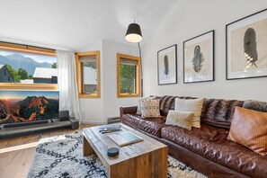 A modern living room with a leather sofa, a wooden coffee table, and a large flat-screen TV. - Chalet Chic Condo, Short Walk To Lift 7, Covered Parking 2 Bedroom Condo by RedAwning (Telluride)
