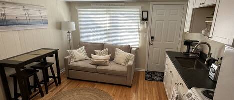 A compact living space with a kitchenette, a sofa, a dining table, and a patterned rug.