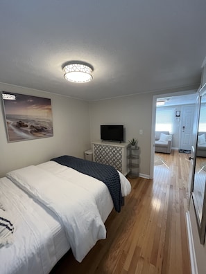 Un dormitorio con una cama, un televisor, un cuadro y un pasillo que lleva a otra habitación.
