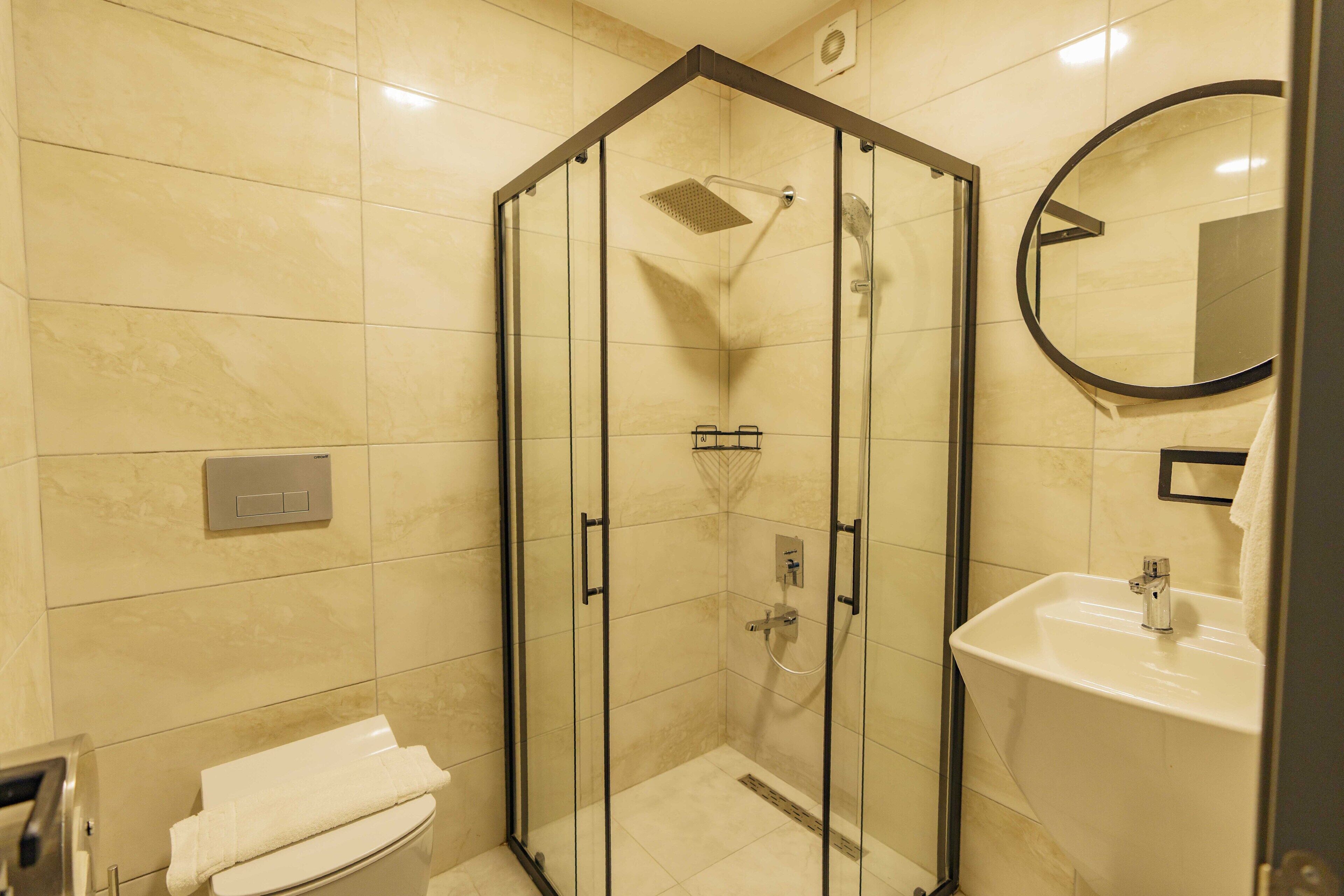 Un baño moderno con ducha de vidrio, inodoro y lavabo con espejo.