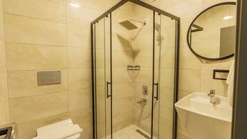 Un baño moderno con ducha de vidrio, inodoro y lavabo con espejo.