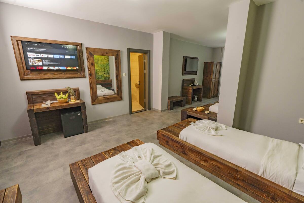 A hotel room with two beds, a desk, a TV, and a mirror.