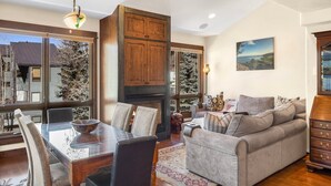 A dining area with a glass-top table, wooden chairs, and a fireplace. - Walk To Festivals! Windows, Fireplace, Hot Tub 1 Bedroom Condo by RedAwning (Telluride)