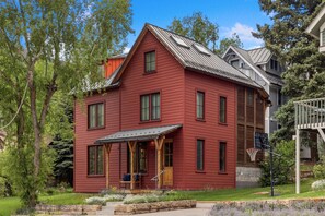 Ett rött hus i två våningar med en veranda, en basketkorg och en stentrappa som leder upp till ytterdörren.