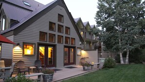 A two-story house with a covered patio, outdoor seating, and a well-maintained lawn.