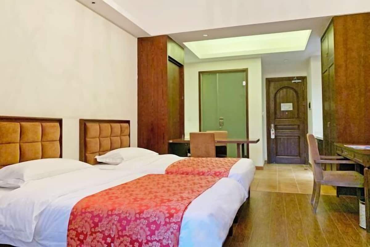 A hotel room with two beds, a desk, and a chair.