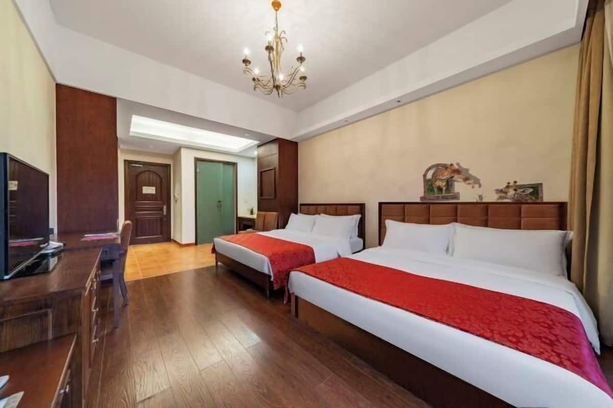A hotel room with two beds, a desk, and a television.