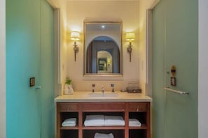Un baño con lavamanos, espejo, toalleros y apliques de pared.
