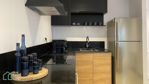 A modern kitchen with black cabinets, a stainless steel refrigerator, a wooden countertop, and a black range hood. - New 1 bd With Garden and sea Side at Marsa Cornich (La Marsa)