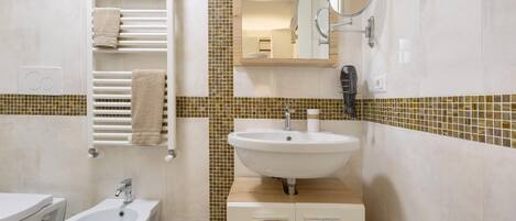 A modern bathroom with a bidet, sink, and towel rack.