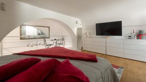 Une chambre à coucher moderne avec un lit, une télévision, un bureau et un miroir.