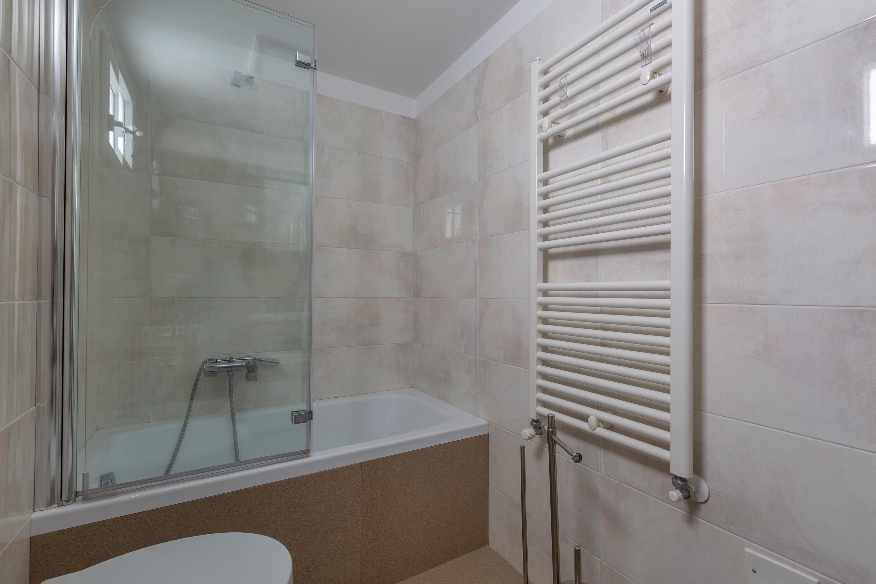 A bathroom with a glass-enclosed shower, a bathtub, and a towel rack.